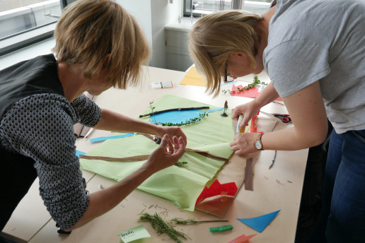 Zwei Frauen beugen sich über einen Tisch und basteln gemeinsam ihre Traumstadt aus Materialien. Foto: (c) WILA Bonn