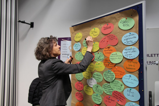 Das Bild zeigt eine Dame vor einer Pinnwand. Darauf gepinnt sind eine Reihe an Karten rund um das Thema Klima.