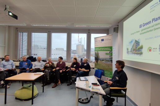 Eine Gruppe von Menschen arbeitet an einem Planspiel und sitzt gemeinsam vor einer Präsentation