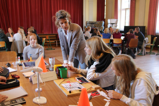 Das Bild zeigt ein Wissenschaftscafe mit einer 12. und 13. Klasse in einer Schule. Jugendliche sitzen dafür an verschiedenen Tischen und diskutieren mit Expert*innen auf Augenhöhe. Foto: (c) WILA Bonn