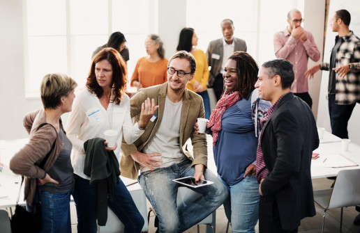 Gruppe von Menschen die freundlich miteinander diskutieren, im Hintergrund stehen drei Zweiergruppen die sich unterhalten
