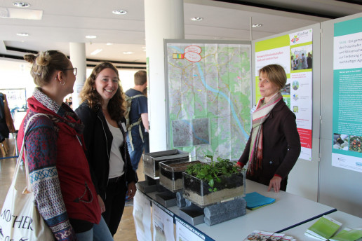 Das Bild zeigt Dr. Anke Valentin an einem Stand mit zwei Studierenden. Vor Anke Valentin stehen drei Glaskästen auf einem Tisch mit verschiedenen Bodensubstraten. Foto: © WILA Bonn