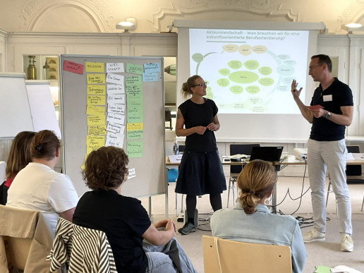 Das Bild zeigt eine Schulung von Akteur*innen im Bereich Berufsorientierung mit Iken Draeger vom WILA Bonn. Sie steht vor einer Pinnwand mit einer Pr&auml;sentation im Hintergrund. Foto: (c) Netzwerk Gr&uuml;ne Arbeitswelt