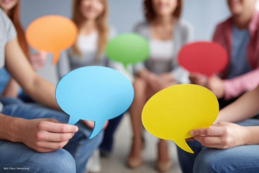Das Bild zeigt eine Gruppe an Menschen verschwommen, die Sprechblasen in die Luft halten. Foto: (c) Best/AdobeStock