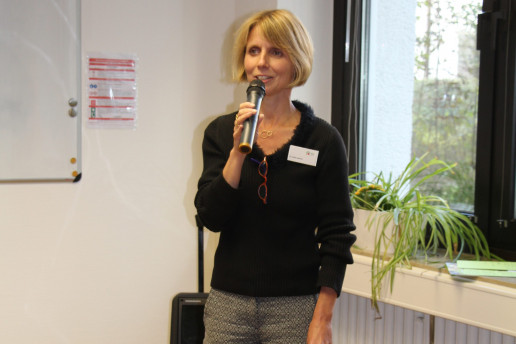 Das Bild zeigt Anke Valentin, die auf einer Veranstaltung moderiert. Sie hält dabei ein Mikrofon in der Hand.