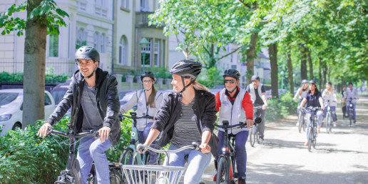 Eine Gruppe radelt durch Bonn. Entlang der Straße stehen Bäume. Foto: (c) Bundesstadt Bonn, Kolja Matzke