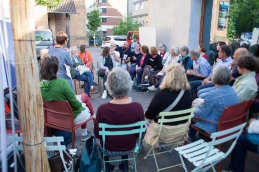 Das Bild zeigt eine Gruppendiskussion. Die Teilnehmenden sitzen in einem Hof in einem Stuhlkreis. Foto: (c) Sara Bahadori